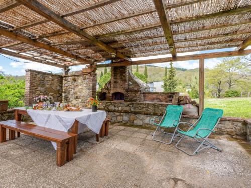 patio con mesa, sillas y chimenea de piedra en Holiday Home Podere Casidote by Interhome en Montieri