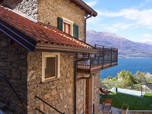 a stone house with a balcony and a view of the water at Holiday Home Casa Rina by Interhome in Perledo