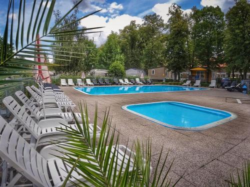 um grupo de cadeiras brancas e uma piscina em Holiday Home Hawaii Style by Interhome em Praga