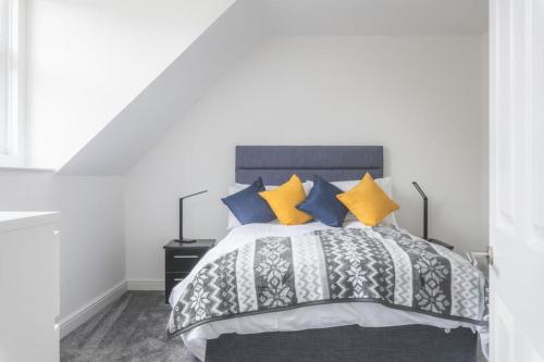 a bedroom with a bed with yellow and blue pillows at Coast View Luxury Apartment in Lyme Regis