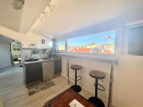 a kitchen with a bar with two stools and a large window at Homelivia, ATTIC ROOM -Mansardé sous les toits de Nice in Nice
