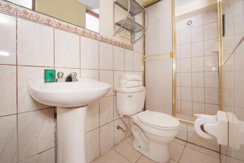 a white bathroom with a toilet and a sink at Ayenda Casa Escondida San Cristóbal Premium in Cusco