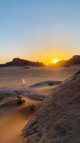 a sunset in the desert with the sun setting at Rum Jordan camp and tours in Wadi Rum