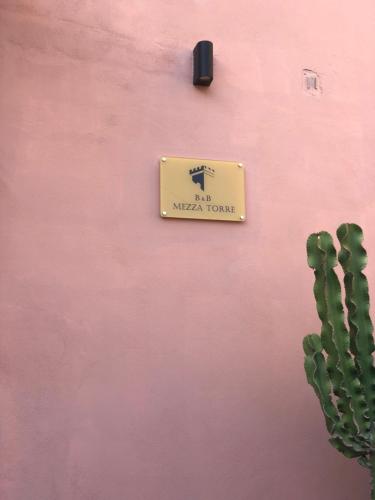 a sign on a pink wall next to a cactus at Mezza Torre B&B in Procida