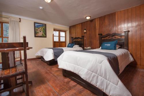 two beds in a room with wooden walls at Ayenda Casa Escondida San Cristóbal Premium in Cusco