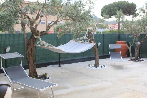 a hammock on a patio with two chairs and trees at AGAS Exclusive Apartment in Catanzaro