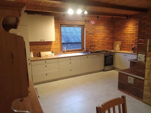 eine große Küche mit weißen Schränken und einem Fenster in der Unterkunft Dom w Czostkowie na Suwalszczyźnie in Rospuda