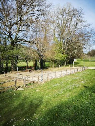a wooden fence in a field with trees and grass at La maison de Zélia in Boissières
