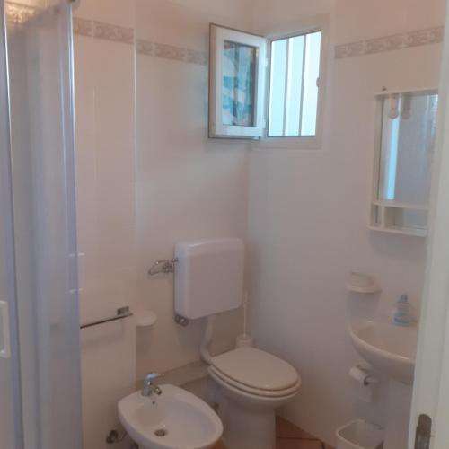 een witte badkamer met een toilet en een wastafel bij A casa dell'artista in Cefalù