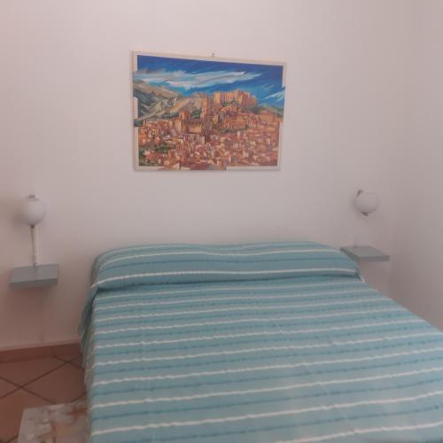 een bed in een slaapkamer met een schilderij aan de muur bij A casa dell'artista in Cefalù