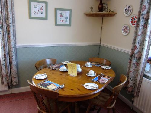 uma mesa de madeira numa sala com cadeiras e uma mesa e cadeira em Black Swan Guest House em Marton