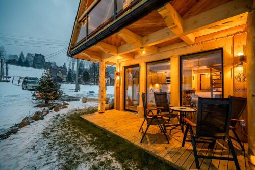 a wooden house with a table and chairs on a deck at Przedsionek Tatr in Zakopane
