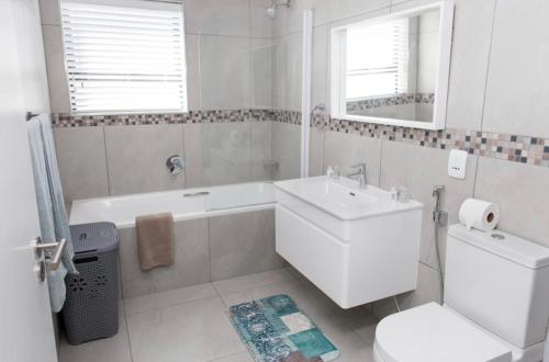 a bathroom with a sink and a tub and a toilet at MLMK Property 17 in Cape Town
