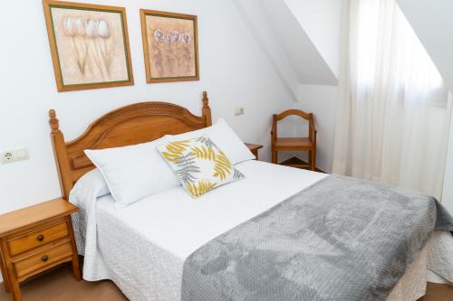 sypialnia z łóżkiem z białymi prześcieradłami i poduszkami w obiekcie Apartamentos A Laxe w mieście O Grove