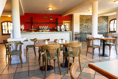 Un restaurante con mesas y sillas de madera y un mostrador. en El Cortijo Apart - Hotel, en Merlo