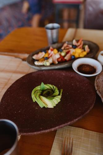 a wooden table with a plate of food with avocado at La Fragata in Vichayito