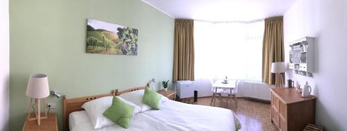una camera da letto con un letto bianco con cuscini verdi di Gästezimmer Klein und Fein für nach dem Wein a Neumagen-Dhron