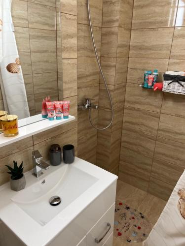 La salle de bains est pourvue d'un lavabo blanc et d'une douche. dans l'établissement Central Apartament 2, à Iaşi