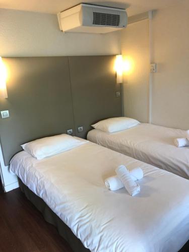 two beds in a room with white sheets and pillows at The Originals Access, Hôtel Foix in Foix