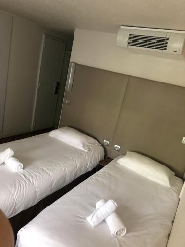 two beds in a room with white sheets at The Originals Access, Hôtel Foix in Foix