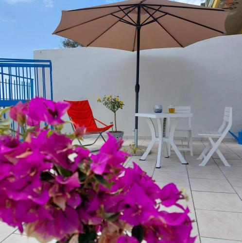 a patio with purple flowers and a table with an umbrella at Blue Sicily Apartment in Roccalumera