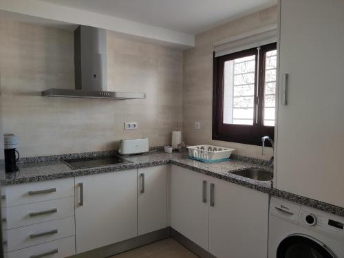 uma cozinha com armários brancos e um lavatório em Benatorre Playa (Casa en primera línea de playa). em Torre de Benagalbón