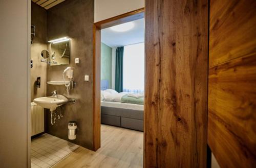 a bathroom with a sink and a bedroom with a bed at Hotel Giamas in Straubing