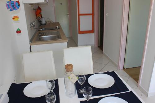 a table with two white plates and glasses on it at Apartments Blue Sea in Mali Lošinj