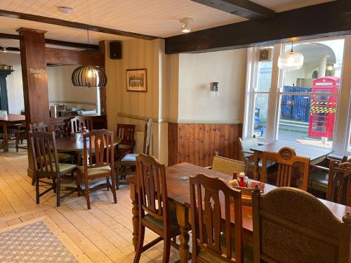 un restaurante con mesas y sillas de madera y una cabina de teléfono roja en Punch House Monmouth en Monmouth