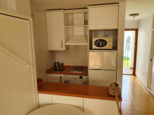 cocina con nevera blanca y microondas en Apartamentos Vacacionales Atlanterra, en Zahara de los Atunes