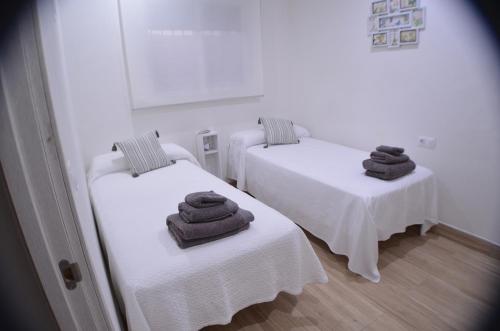 Dos camas con toallas en una habitación. en EL ENCANTO Chiclana, en Chiclana de la Frontera