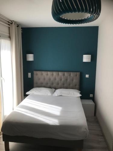 a bed in a bedroom with a blue wall at Hôtel Aunis-Saintonge in Royan