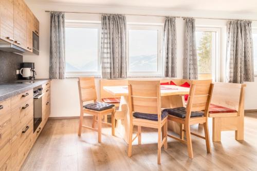 een keuken met een tafel, stoelen en ramen bij Ferienhaus Weitblick in Flachau