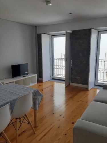 a living room with a table and some windows at São Bartolomeu Apartment 2 in Coimbra