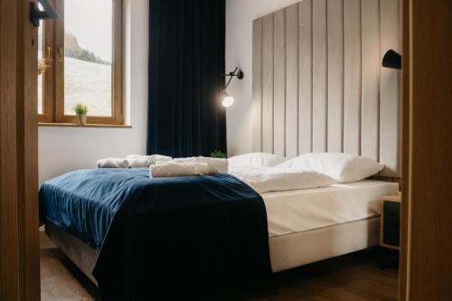 a bedroom with a bed with white sheets and a window at Rajskie Uroczysko Apartamenty Jacuzzi Sauna in Rajskie Sakowczyk