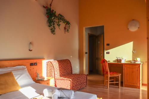 a bedroom with a bed and a chair and a desk at hotel Parco Pineta in Cavareno