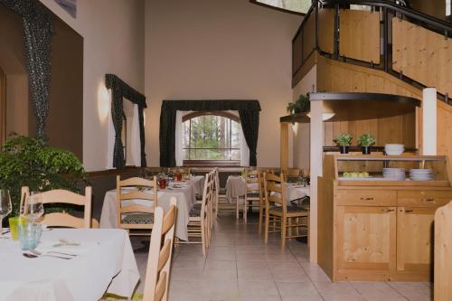a restaurant with white tables and chairs and a window at hotel Parco Pineta in Cavareno