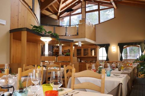 a restaurant with white tables and chairs and a large window at hotel Parco Pineta in Cavareno