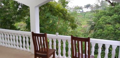 two chairs sitting on a porch looking out at a window at Hill Bottom Accommodation in Suva