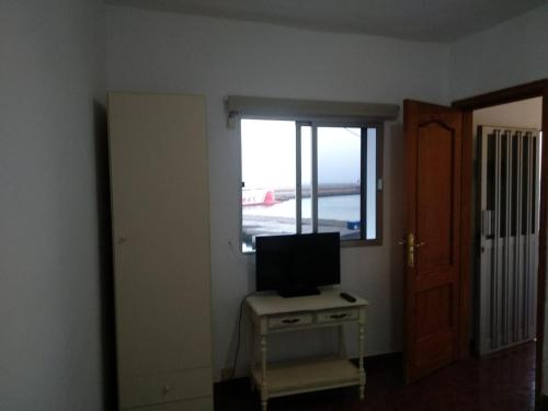 una camera con televisore su un tavolo con finestra di Apartamento puerto estaca 3 a Puerto de la Estaca