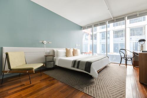 1 dormitorio con 1 cama grande y 1 silla en Sonder The Slate, en Toronto