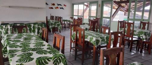 a restaurant with tables and chairs with green and white sheets at Hotel Porto Verde -JG in Porto Seguro