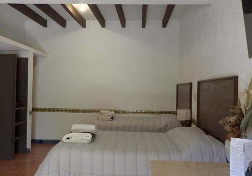 a bedroom with two beds with white sheets at Santuario Jardín de la Abundancia in Tepoztlán