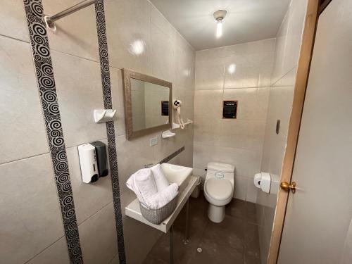 a bathroom with a toilet and a sink and a mirror at Chikan Hoteles in Arequipa