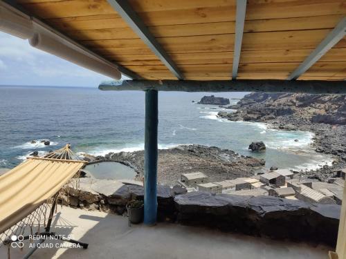 a view of the ocean from a porch with a hammock at Casa Cueva el Pozo las Calcosas in Pozo de las Calcosas