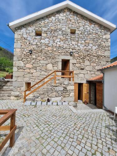 a stone building with a wooden staircase in front of it at Quinta de Leandres in Manteigas