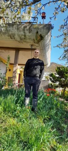 a man standing in the grass in front of a house at My home udabno in Udabno