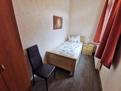 a small bedroom with a bed and a chair at Pension Ginko in Wernigerode