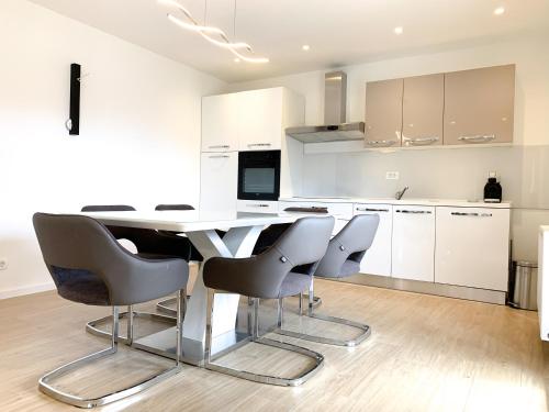 a white kitchen with a table and chairs at G Apartment in Podstrana