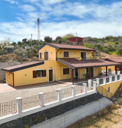 a yellow house with a white fence in front of it at Agriturismo Bella Vista - Da Carmelo in Santa Teresa di Riva